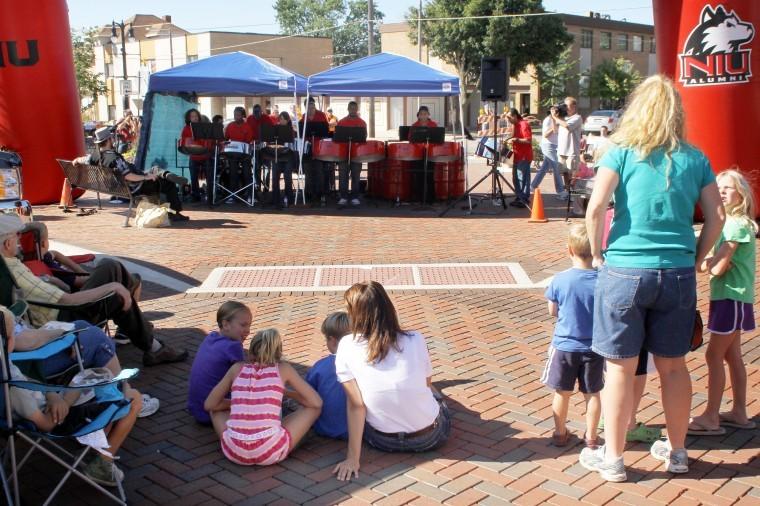 Family and friends gather to watch the NIU Steel Drum Band at the intersection of Second Street and Locust Street Thursday afternoon.