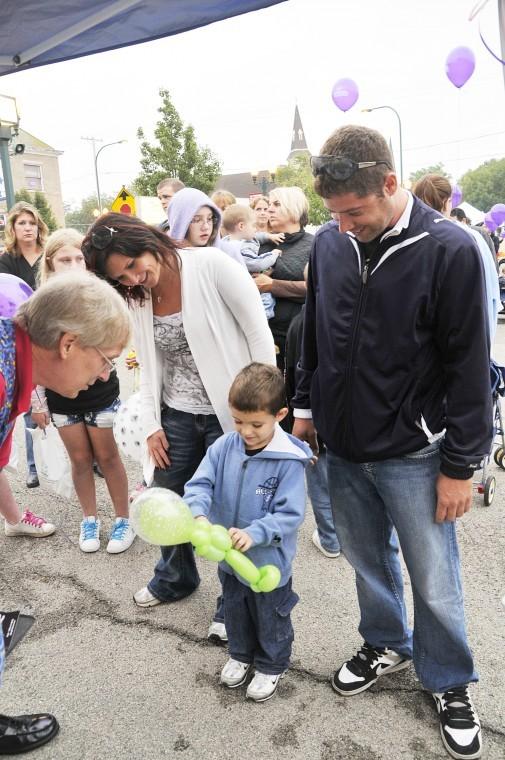 Magician and Balloon Sculpter Tim Glander, of Whitewater, Wisconsin hands an alien balloon to Austin Allen as his father Mike Allen and Heather Romon watch on during the Sycamore Block Party Saturday.