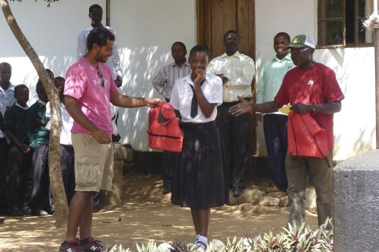 Rohan Escobar (left), senior electrical engineering major, hands
an NIU bag to Jacqueline Frank (center) of Nyegina Secondary
School. Dr. Andrew Otieno (right) challenged the students to find
out where Belize was and awarded them with prizes. 
