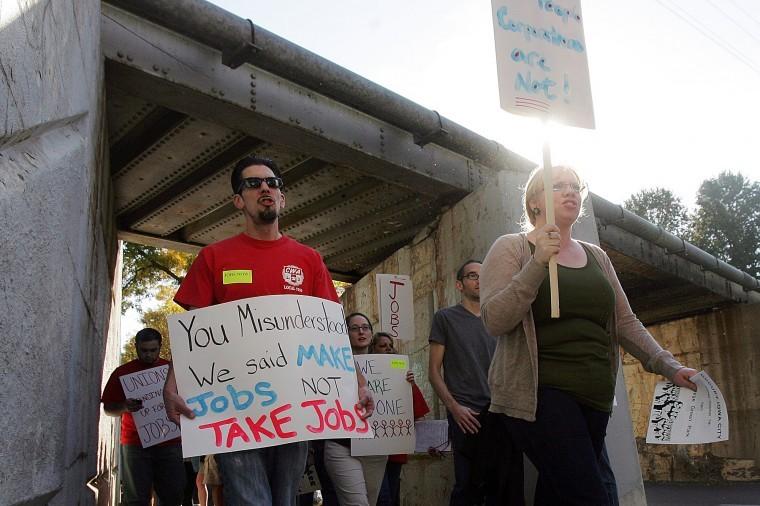 Protesters march under the Iowa Avenue railroad bridge during a
rally urging job creation and tax reform for large corporations on
Friday, Oct. 7, 2011, in Iowa City, Iowa. The bridge was cited as
an example of a needed infrastructure upgrade that would also
create jobs. AP Photo - The Gazette, Liz Martin
