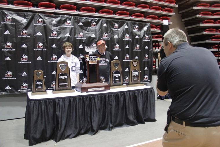 Mitchell Johnson (left), 13, and Bud Weinstock, 66, of Sycamore,
pose for a picture with NIU championship trophies before the mens
basketball game Wednesday night at the Convocation Center. NIU
Media Services took pictures of the fans and later posted them
online for fans to download.
