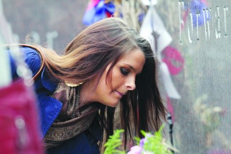 A woman leaves flowers at the memorial stone of Dan Parmenter
Tuesday afternoon during the Memorial Wreath ceremony outside of
Cole Hall.