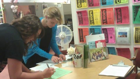 Katie Gauthier, program coordinator for NIU administered study abroad programs, helps Alecia Eschenbrenner sign forms in preparation for a study abroad program.