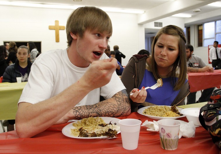 Senior automotive major Tim Madsen and Amanda Kalkstein, senior English and health education majors, sample food from around the world at Taste of Asia, held at the Newman Catholic Center Tuesday night.
