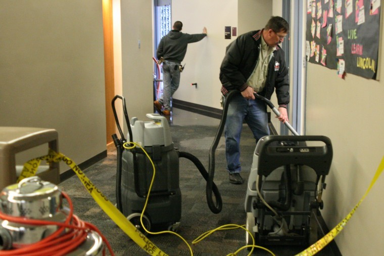NIU Building Services workers clean up the Lincoln Hall A-wing first floor after the sprinkler system activated in 2011. Interim Fire Chief Eric Hicks has proposed sprinkler systems be installed in local Greek residences.
