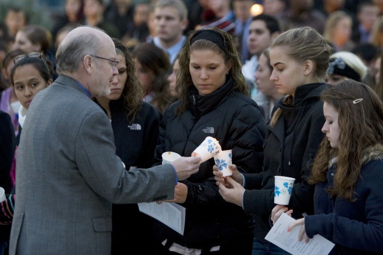 Reverend Tom Acton David Bogenbergers pastor assists students in lighting candles for candle lighting and moment of silence in the MLK Commons.

