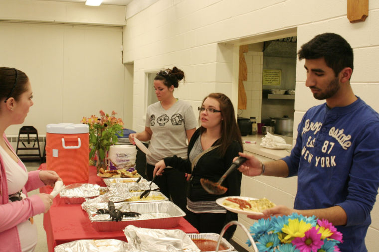 (From left to right, across table) Rachel Udley (left), sophomore family social services major, Shelbey Lippeth, junior elementary education major, and Manas Chug, freshman biology major help serve food Wednesday night at the Relay For Life benefit dinner in the basement of the Newman Center.
