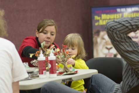 Kathryn Olson, senior environmental studies major, shows two-year-old Eleanor Burlingame how to make paper-bag trees on Saturday at the Green Family fun day in Haish Gym.