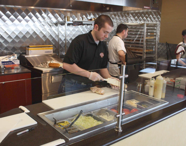 Josh Kreiner, manager of Carmines, Subs, Wraps, and Salads makes a hot Philly cheese steak sandwich on Monday at their Sycamore location at 2672 DeKalb Ave.
