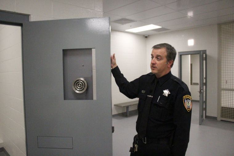 Community relations Officer Chad McNett describes a holding pen, which will be cushioned for intoxicated criminals, in the booking room of the new police station Tuesday. The station is set to open in 10 to 14 days. 