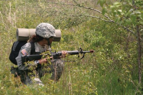 A female ROTC cadet crouches during a ROTC field exercise.