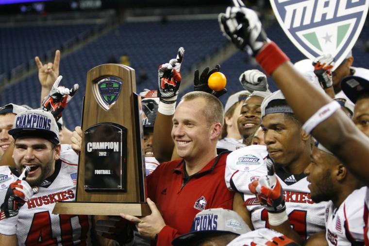 Dave Doeren, former NIU football head coach, poses with the MAC Championship trophy and members of his team at the MAC Championship in Detroit in 2012. After securing the trophy for the second year in a row, NIU was chosen to play in the BCS’s Orange Bowl.