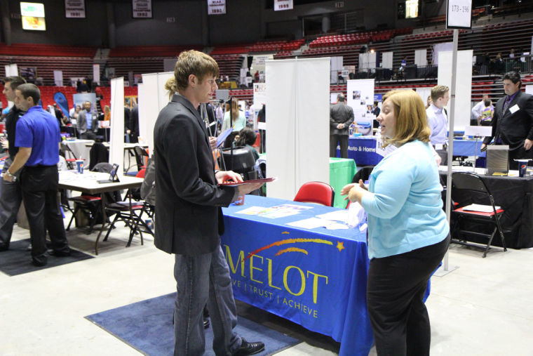 Broc Pagni, senior health science major, hands his resume to Camelot representative Amanda Wisse at the Job Fair in the Convocation Center. Pagni was interested in Camelot’s Therapeutic Day School positions.