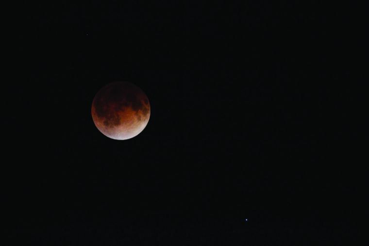 The moon glows reddish-brown during a lunar eclipse on April 15, 2014. Students will get a free, hands-on experience to observe a supermoon lunar eclipse through a telescope Sunday in the NIU Observatory. 