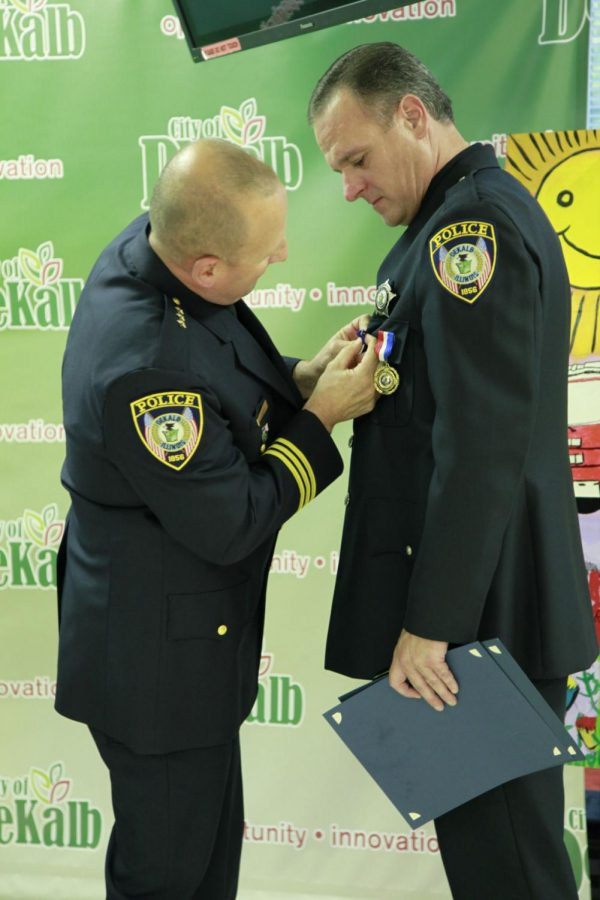 DeKalb Police Chief Gene Lowery awards officer Jeffery Winters, during Monday’s City Council meeting, for an act of kindness and call to service.