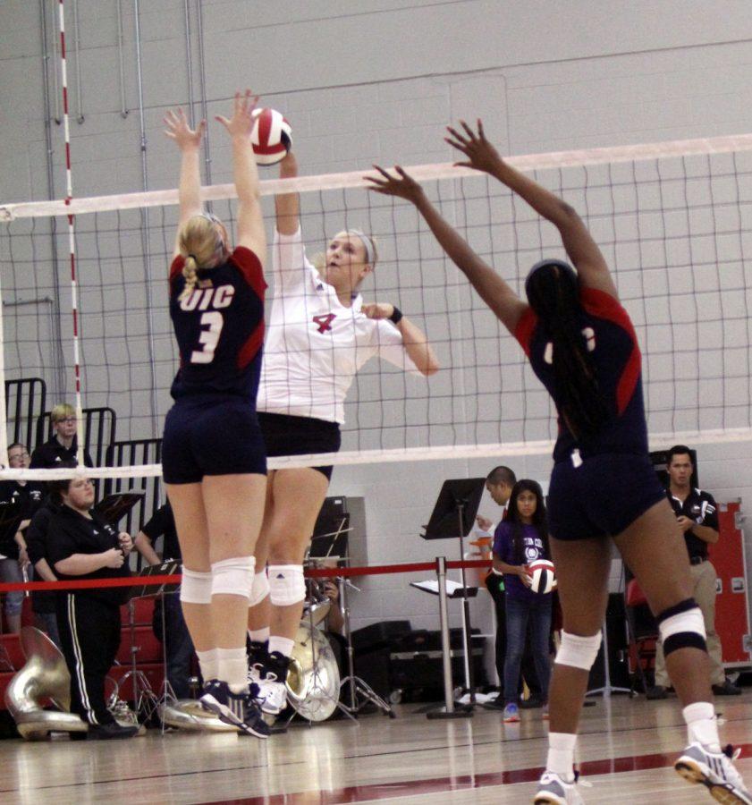 Freshman middle blocker Shleby Seurer (4) attempts to hit the ball over the net against the Illinois-Chicago Flames Tuesday at Victor E. Court. Seurer and the Huskies downed the Flames in four sets, 3-1.