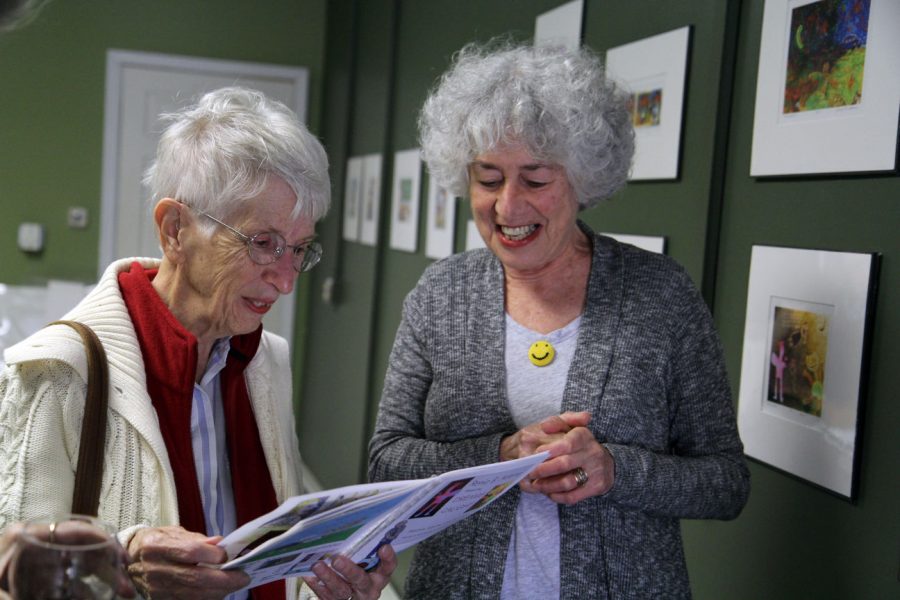Spencer Elaine (left), 75, of Sycamore, visits with artist Renie B. Adams Oct. 5 at the Art Box, 308 E. Lincoln Highway. Adams walked attendees through the gallery as they followed along with her collective art book.