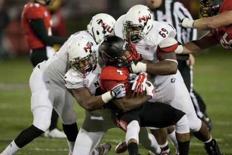 A host of Huskies tackle running back Horactio Banks Wednesday at Scheumann Stadium in Muncie, Ind. The defense forced five turnovers and converted them into 21 points in the 35-21 victory over Ball State.