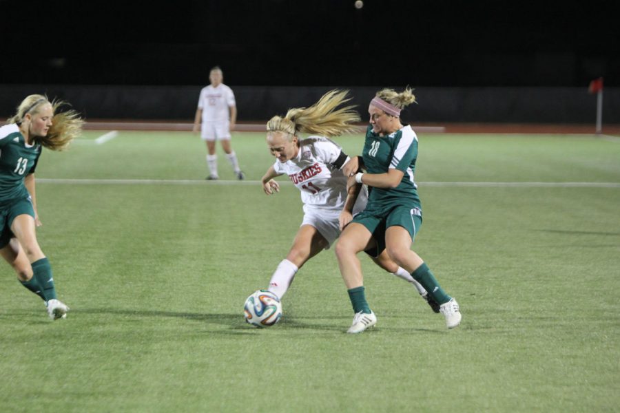 Senior midfielder Allie McBride (11) fights off an opponent Oct. 24 at the Soccer and Track & Field Complex. The Huskies earned a trip to the MAC semifinals with a 4-3 win over Miami (Ohio) Sunday.
