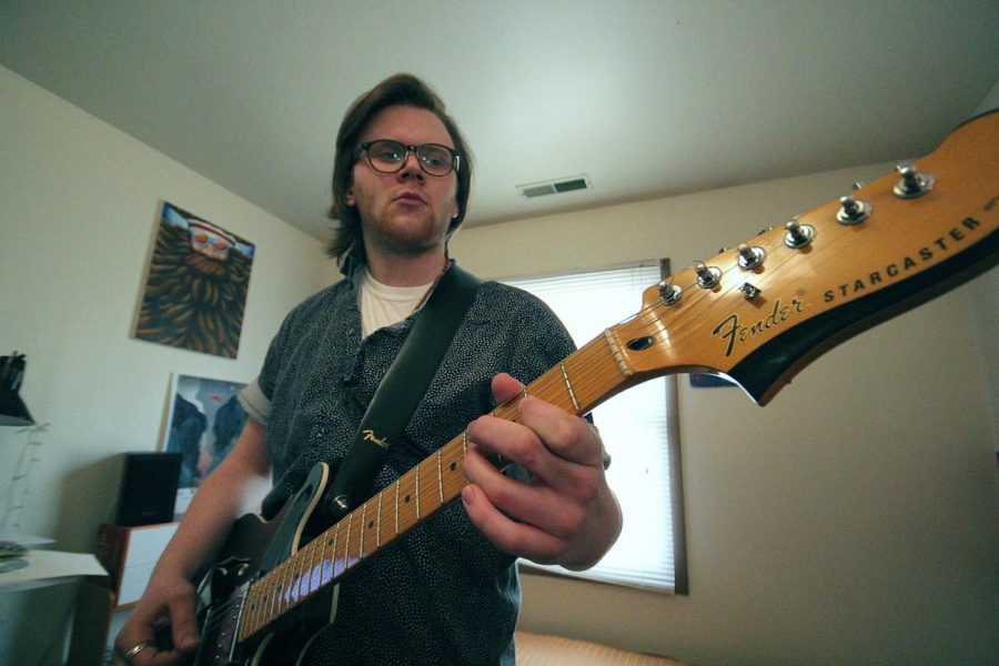 Senior illustration major Griffin Thorne plays guitar in his room Wednesday. Thorne plays guitar, violin and does art for acousitc-punk band Little Yellow Dog, which will release its album, “This Is A Phase,” Jan. 31.
