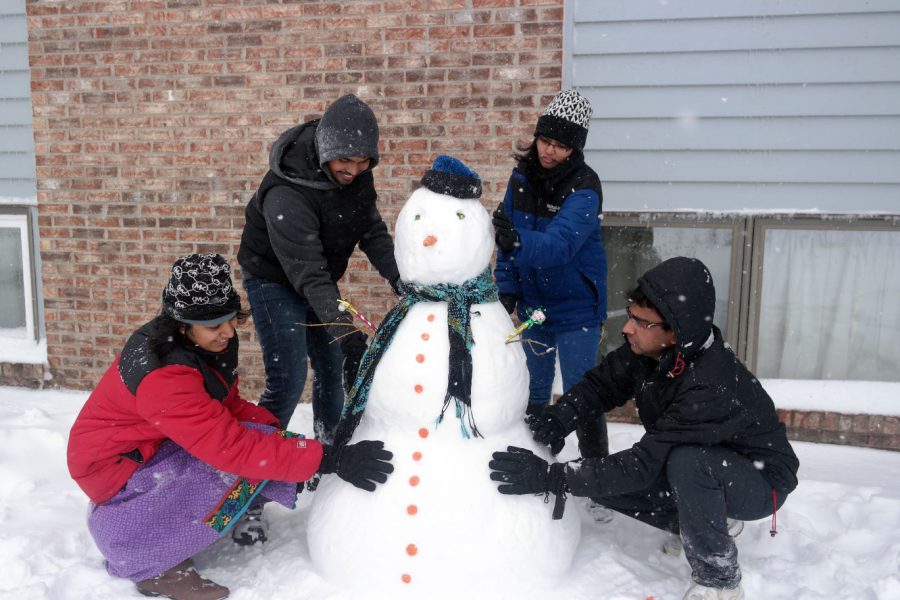 (Left to right) Sneha Redd, graduate computer science student; Akhil Munnetula, graduate industrial engineering student; Mansa Reddy, graduate computer science student; and Sripada Sai Subhash, graduate electrical engineering student, build a snowman during Sunday’s blizzard near West Ridge Apartments on Ridge Drive. The snowstorm was expected to drop more than a foot of snow on northern Illinois.