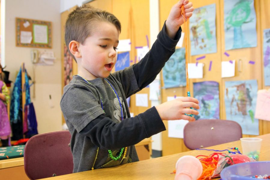 Ethan Barry, 5, makes a necklace Friday at Campus Child Care. The center provides services for student-parents, but Illinois childcare providers could close within three weeks due to a budget shortfall. The General Assembly is considering a $278 million supplemental budget that would help childcare providers.