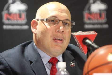 NIU athletics director speaks into a microphone during a press event.