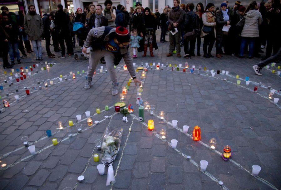 A man lights a candle which forms a peace sign during a candlelight vigil for the Paris attacks Wednesday in the town square of Molenbeek, Belgium. After a Wednesday morning raid in the Paris suburb of Saint Denis, authorities could not immediately confirm whether Abdelhamid Abaaoud, a Belgian Islamic State militant, was killed or arrested. Both Abaaoud and the Abdeslam brothers, that also participated in the attacks, grew up in the same neighborhood of Molenbeek. 