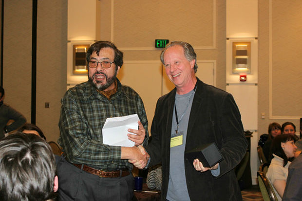 William Barletta, director of the U.S. Particle Accelerator School (left), gives the Iron Man award to NIU physics professor Michael Syphers at the opening ceremony of the U.S. Particle Accelerator School held by the University of Texas at Austin at the Sheraton Austin Hotel at the Capitol on Jan. 24.