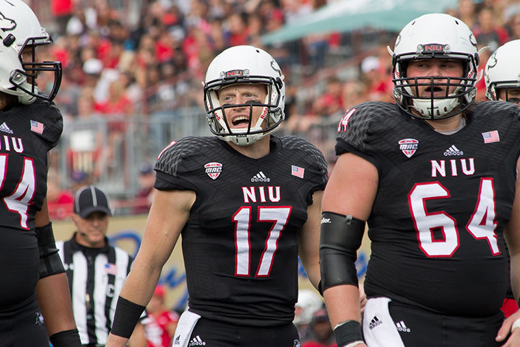 Redshirt sophomore quarterback Ryan Graham (middle) shouts instructions at Luke Shively, redshirt sophomore offensive lineman (right), prior to a snap during Saturday’s football game at Huskie Stadium. 