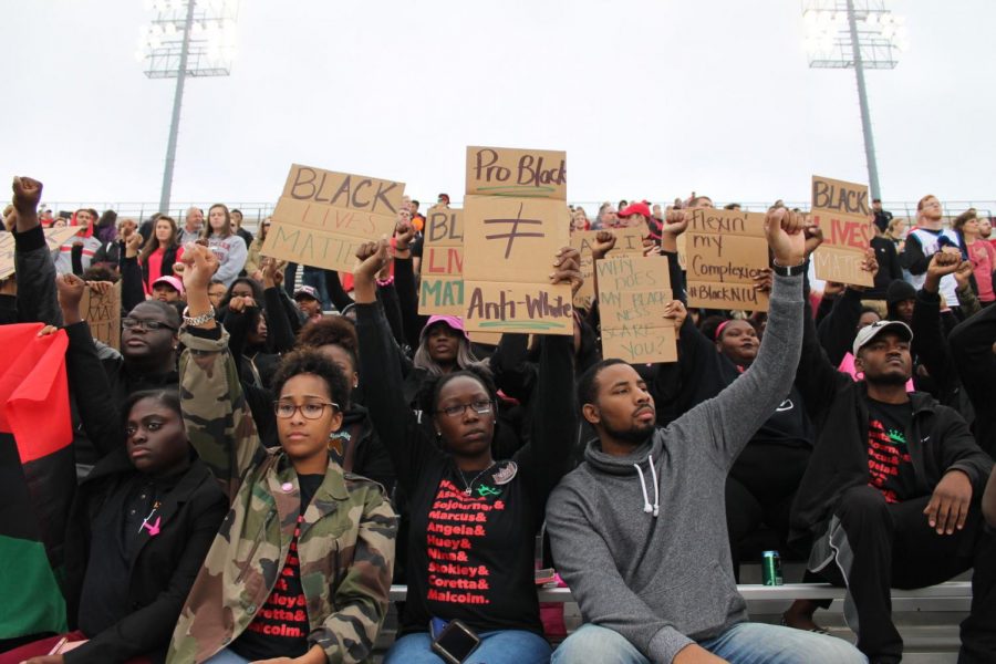Students raise their fists and chant, black lives matter, after the national anthem at the football game Saturday in Huskie Stadium against Central Michigan University.