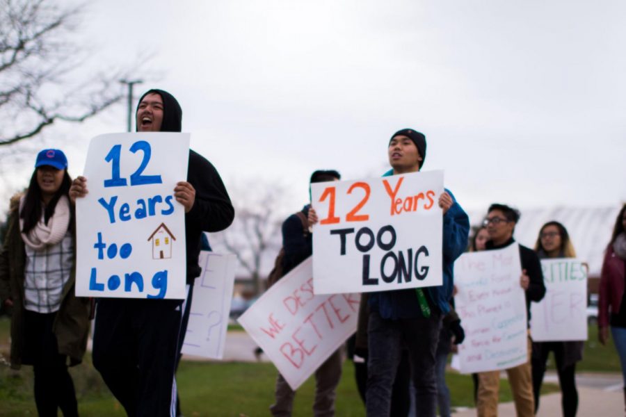Protestors hold “12 years too long” signs, advocating for a better resource facility for the Asian American community Tuesday in the MLK Commons. NIU gave the resource center to students 12 years ago as “temporary” space. 