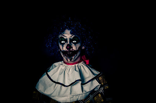 Crazy ugly grunge evil clown on Halloween making people scared