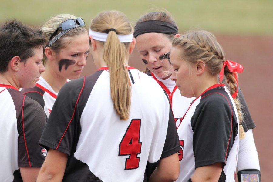 Members of the softball team gather at the mound in Fridays first game against University of Akron Zips. The Huskies went on to defeat the Zips in this game 3-1.
