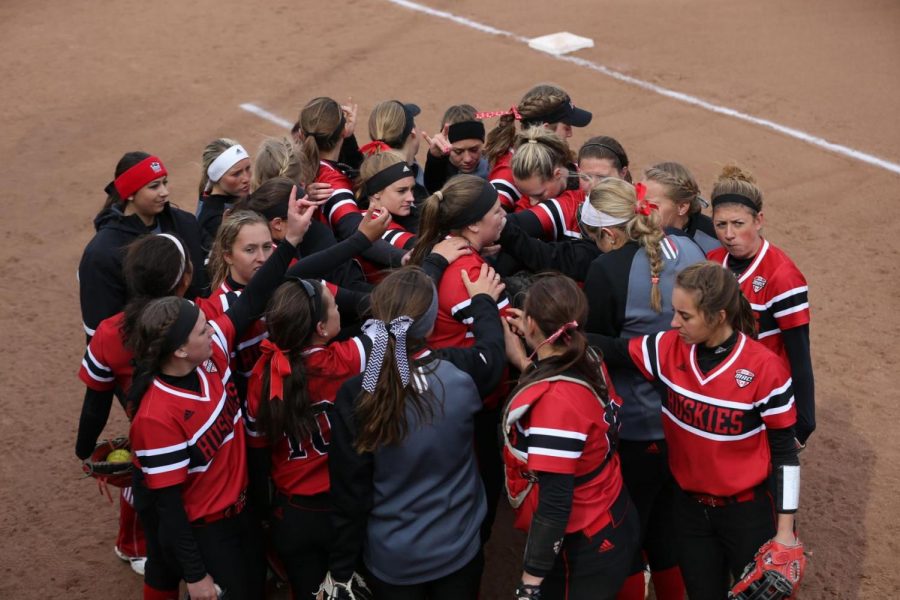 Players and coaches huddle together to discuss strategies before a game earlier this season. The softball team won its two games in the Hawkeye Invitational in Iowa City, Iowa Friday and Saturday. 