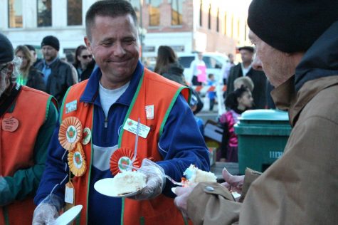 President of Pumpkin Fest Committee, Bart Desch, hands DeKalb county resident Gary Mullis a slice of cake during the opening ceremony