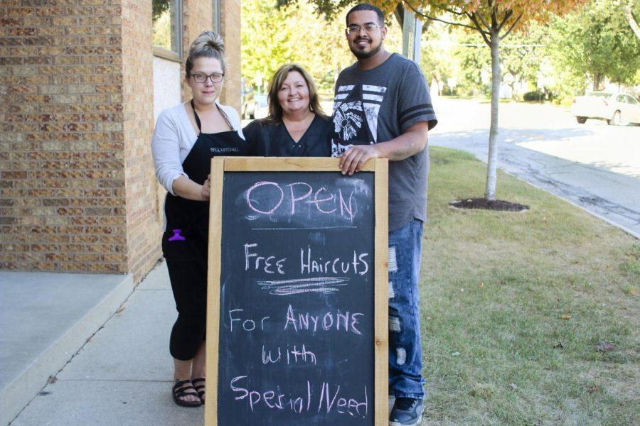 Hairstylist Jess Snow (left), Serenity Salon II Owner JoAnn Page (center), and hairstylist Tito Souchet (right), pose with a sign advertising free haircuts for individuals with disabilities at Serenity Salon II, 205 N. Second St.