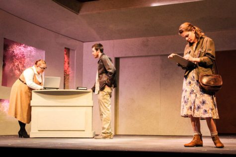 Mary Swanson (right), played by Ellen Campbell, checks her clipboard while the librarian (left), played by Rachel Jaco, speaks with John Dodge, played by Ken Miller.