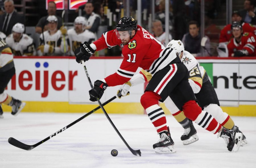 Chicago Blackhawks left wing Brendan Perlini (11) makes a pass in front of Vegas Golden Knights left wing Daniel Carr (23) during the first period of an NHL hockey game Tuesday, Nov. 27, 2018, in Chicago. (AP Photo/Jeff Haynes)