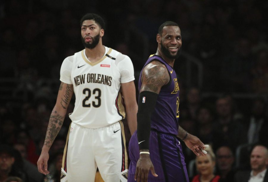 Los Angeles Lakers LeBron James, right, smiles as he walks past New Orleans Pelicans Anthony Davis during the first half of an NBA basketball game Friday, Dec. 21, 2018, in Los Angeles. (AP Photo/Jae C. Hong)