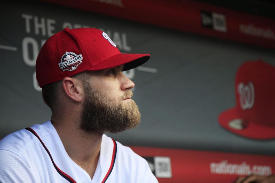 FILE - In this Sept. 26, 2018, file photo, Washington Nationals Bryce Harper, looks at the baseball field from their dugout before the start of the Nationals last home game of the season against the Miami Marlins in Washington Spring training has started, yet two of baseballs biggest stars, Bryce Harper and Manny Machado, are sitting at home. (AP Photo/Manuel Balce Ceneta, File)