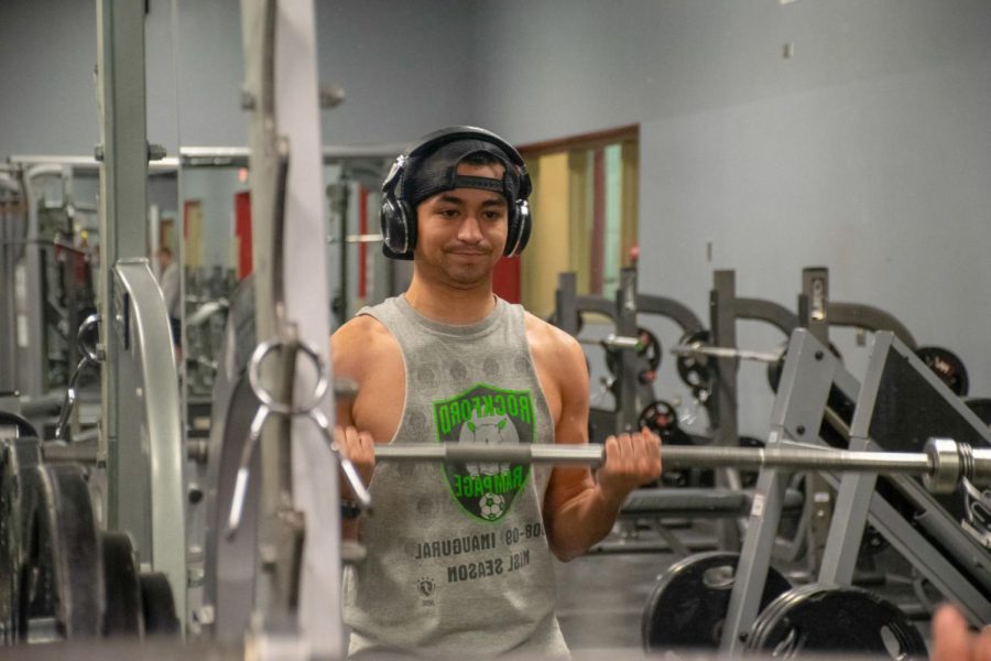 Senior OM&IS major Luis Montenegro works out his biceps at 9 a.m. by using the barebell Wednesday at Fitworkz, 1690 Sycamore Road, in DeKalb.