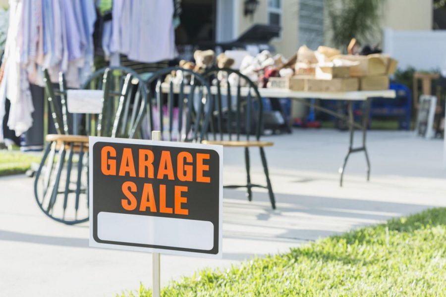 A sign stands in front of a garage sale.