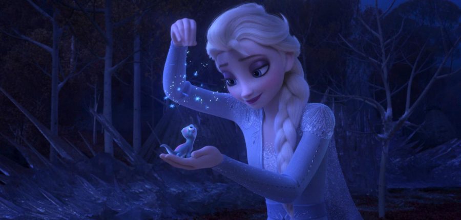 This image released by Disney shows Elsa, voiced by Idina Menzel, sprinkling snowflakes on a salamander named Bruni in a scene from the animated film, Frozen 2. (Disney via AP)