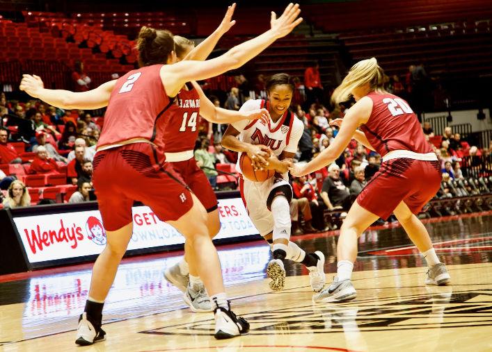 Senior guard Myia Starks charges through three Crimson defenders Tuesday in the Huskies’ season opener. The team lost 59-53 at the Convocation Center.