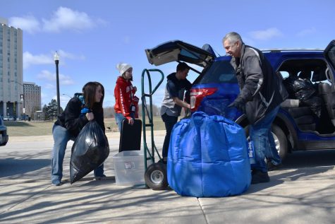 Christy Thompson (left), of Roscoe, and Tim Terry (right), of Carol Stream, share a laugh as they help Breanna Terry (center left), first-year child development major, and Jason DuPont, first-year physics major, pack the car. Breanna said the early move-out is