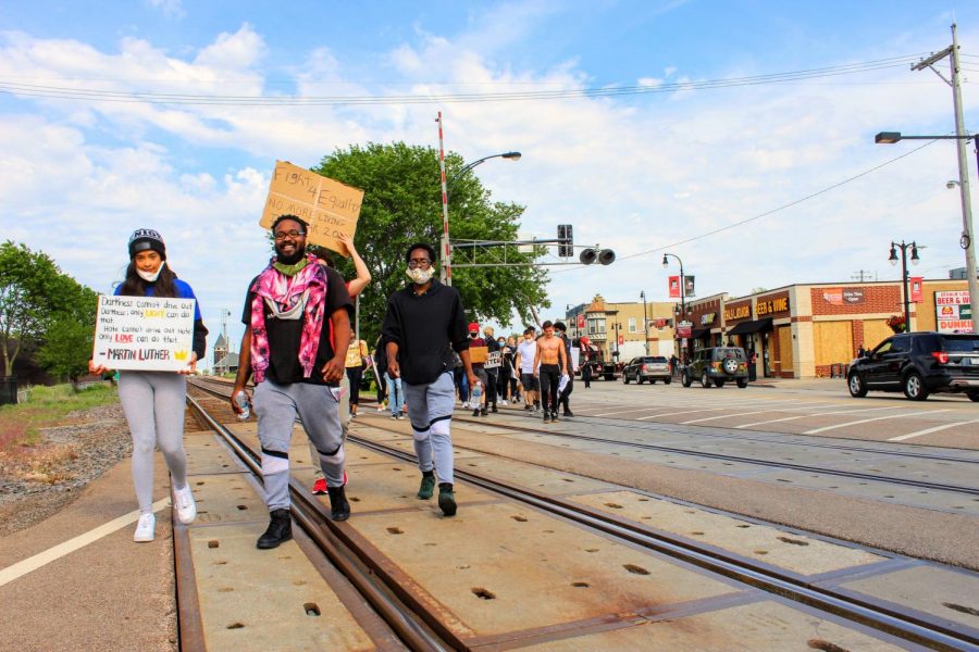 Protesters, Tiana McAllister (from left) and Bryton Rimmer, march Monday over train tracks in DeKalb.