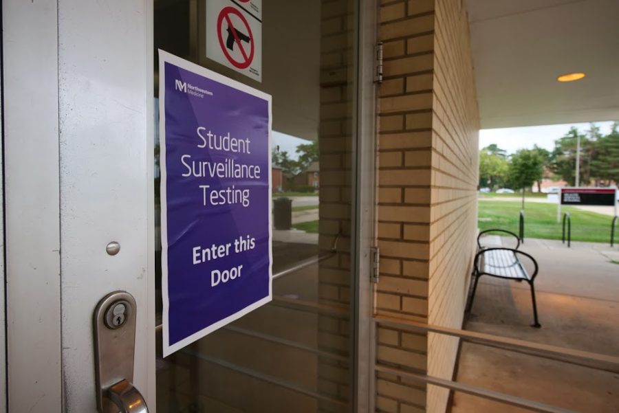 A surveillance testing sign hangs on the entrance of the NIU Health Services building.
