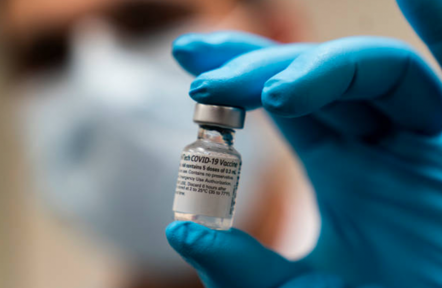 A doctor holds a vaccine vial in their gloved hand. 