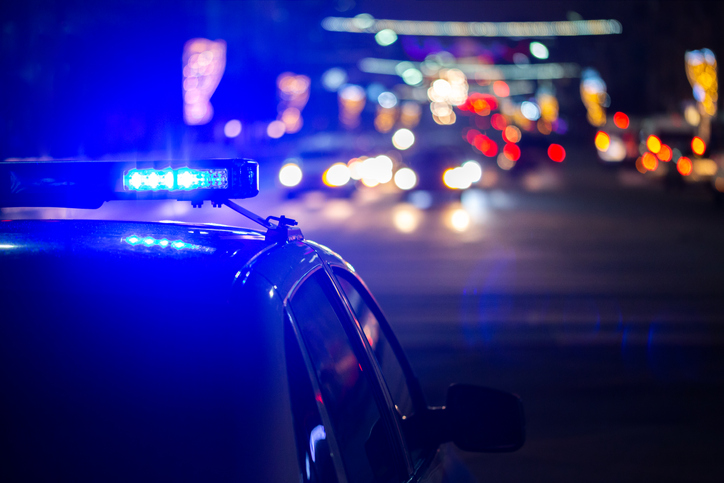 A police car has its lights  on at a busy road at night.